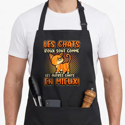 Tablier de cuisine noir avec illustration d'un chat roux debout et texte humoristique sur fond de points colorés.