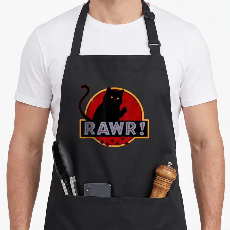 Tablier de cuisine noir avec illustration d'un chat noir stylisé et l'inscription Rawr sur fond rouge circulaire.