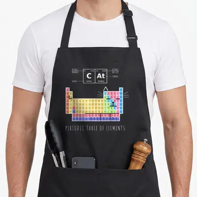 Tablier de cuisine noir avec un tableau périodique des éléments formant la silhouette d'un chat coloré.