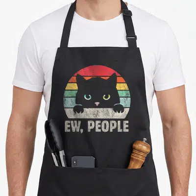 Tablier de cuisine noir avec illustration d'un chat gris aux yeux verts et texte Ew Gens en style rétro délavé.