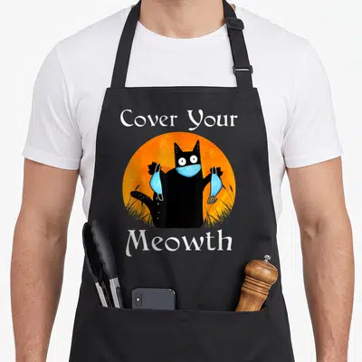 Tablier de cuisine noir avec un chat noir tenant des masques bleus devant une lune orange.