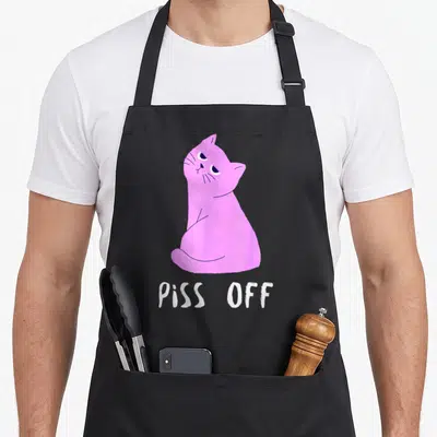 Tablier de cuisine noir avec un chat rose assis et le texte Piss Off en blanc sous l'illustration.