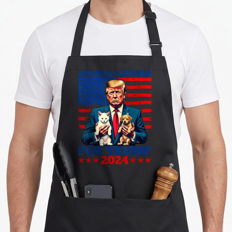 Tablier de cuisine noir avec illustration d'un homme tenant un chat blanc et un chien devant un drapeau aux couleurs bleu et rouge.