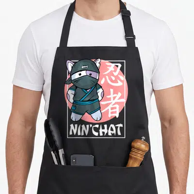 Tablier de cuisine noir avec illustration d'un chat ninja portant un masque et le texte Nin'Chat sous un cercle rose.