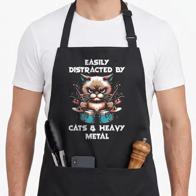 Tablier de cuisine noir avec illustration d'un chat batteur de batterie et texte EASILY DISTRACTED BY CATS & HEAVY METAL