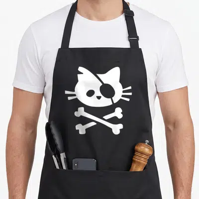 Tablier de cuisine noir avec tête de chat pirate blanche et os croisés en dessous.