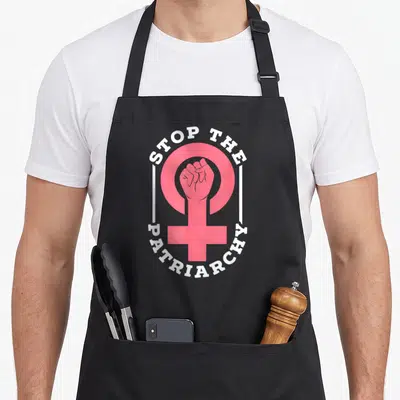 Tablier de cuisine noir avec poing fermé rose dans le symbole féminin et texte Stop The Patriarchy en blanc.