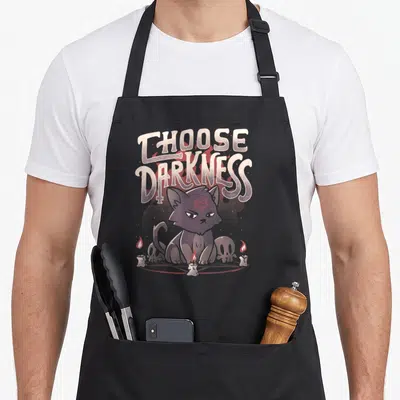 Tablier de cuisine noir avec un chat noir au pentagramme rouge et l'inscription Choose Darkness entouré de bougies.
