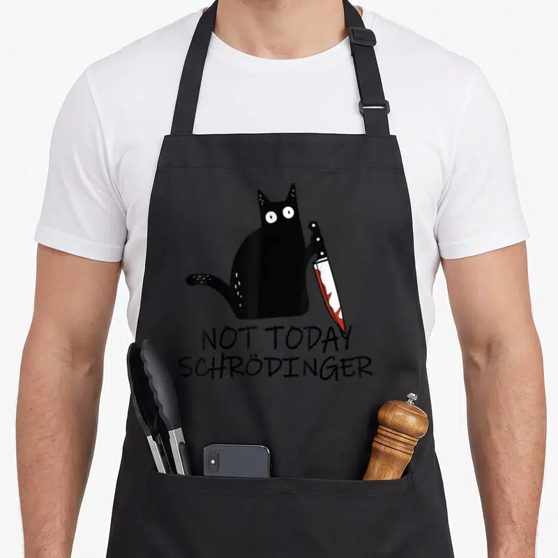 Tablier de cuisine noir avec un chat noir tenant un couteau et le texte Not Today Schrödinger imprimé en dessous.