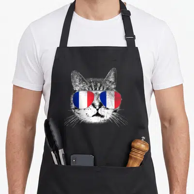 Tablier de cuisine noir avec un chat en noir et blanc portant des lunettes aux couleurs du drapeau français.