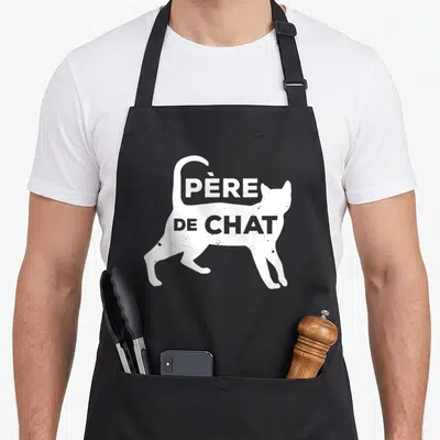 Tablier de cuisine noir avec silhouette de chat blanc et inscription Père de Chat en lettres capitales.