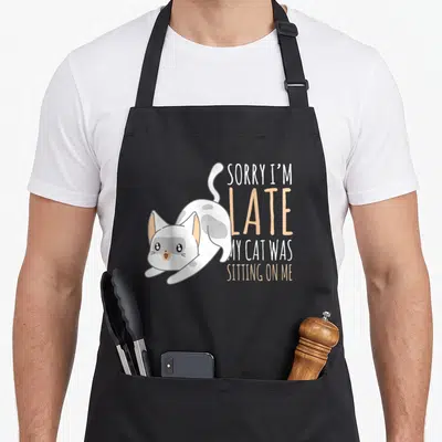 Tablier de cuisine noir avec un chat blanc et gris Kawaii et un texte anglais humoristique.