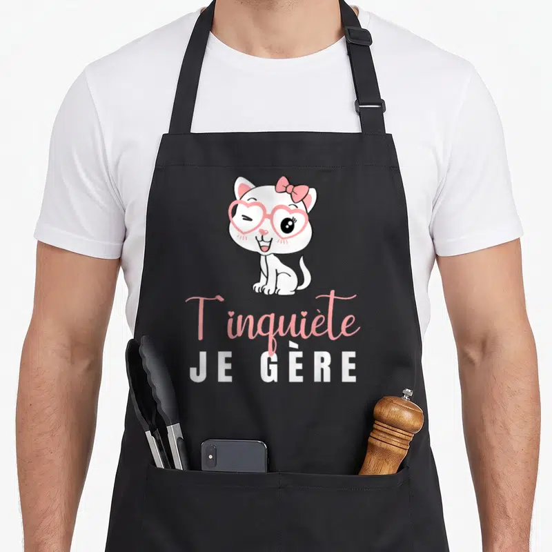 Tablier de cuisine noir avec un chat blanc aux lunettes roses et le texte T'inquiète Je Gère