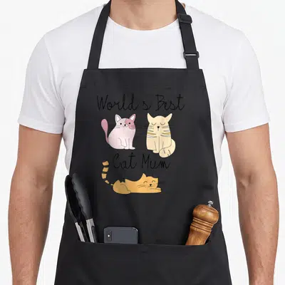 Tablier de cuisine noir avec trois chats dessinés et le texte World's Best Cat Mum en écriture cursive.