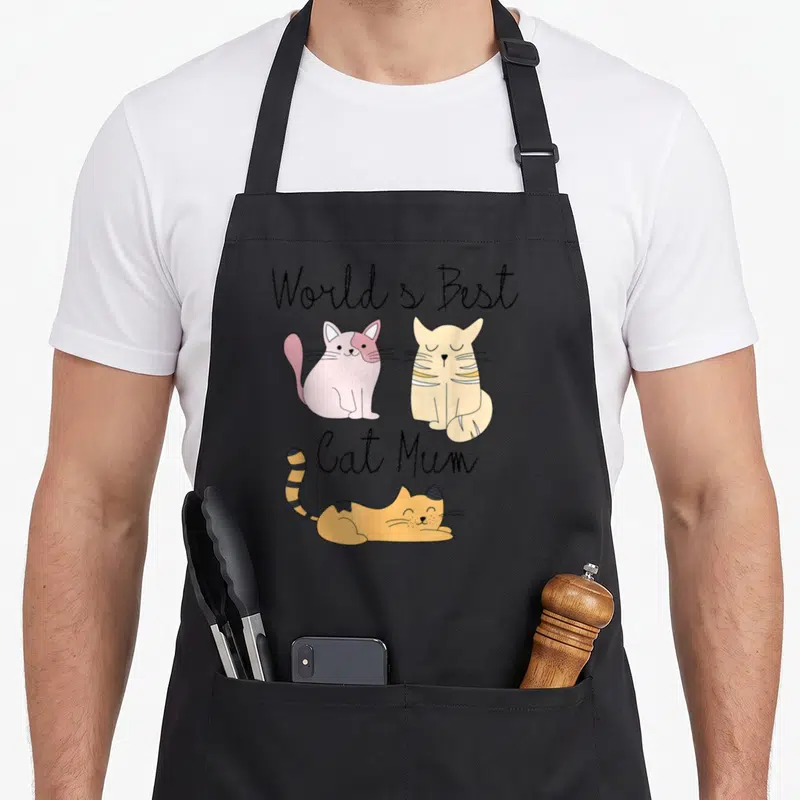 Tablier de cuisine noir avec trois chats dessinés et le texte World's Best Cat Mum en écriture cursive.