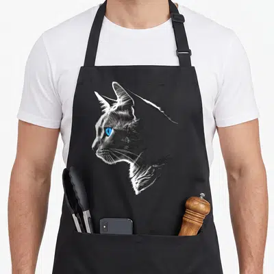 Tablier de cuisine noir avec illustration stylisée d'un chat de profil aux yeux bleus lumineux et traits noirs expressifs.