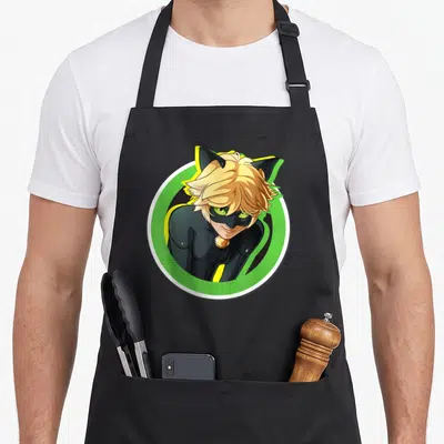 Tablier de cuisine noir avec le portrait circulaire de Chat Noir aux yeux verts et oreilles noires.
