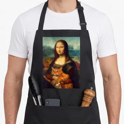 Tablier de cuisine noir avec une illustration de la Mona Lisa tenant un chat roux dans ses bras sur fond de paysage flou.