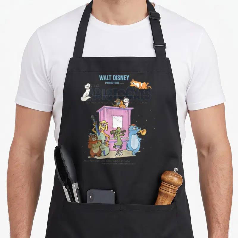 Tablier de cuisine noir avec illustration colorée du groupe de chats musiciens des Aristocats sur fond gris uni.