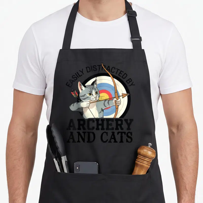 Tablier de cuisine noir avec un chat gris tenant un arc devant une cible de tir à l'arc.