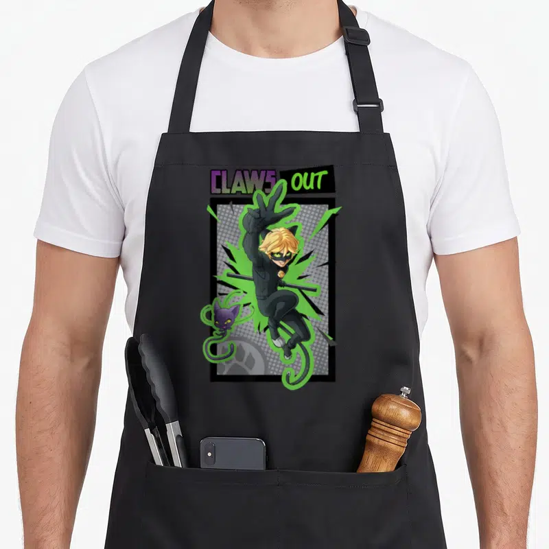 Tablier de cuisine noir avec illustration de Chat Noir sautant et du texte Claws Out en lettres colorées.
