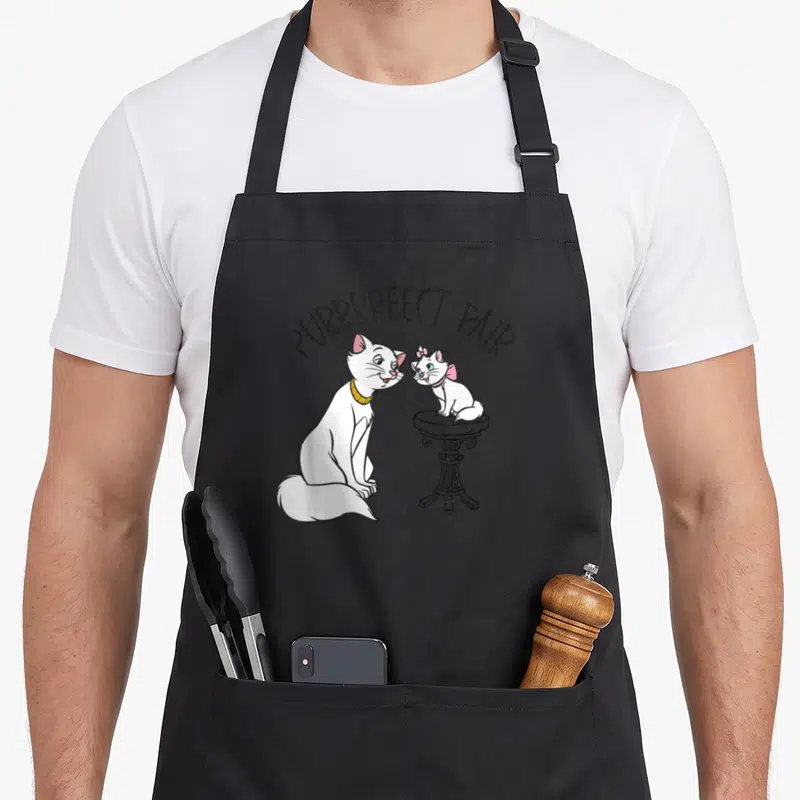 Tablier de cuisine noir avec Marie et ses chatons blancs sur une petite table