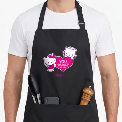 Tablier de cuisine noir avec deux Hello Kitty tenant un grand cœur rose portant une inscription blanche.