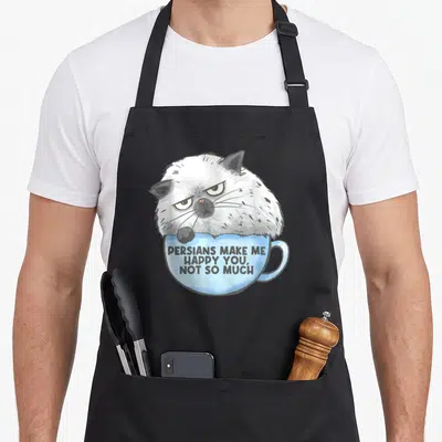Tablier de cuisine noir avec un chat persan blanc et gris posant sur une tasse bleue portant un message humoristique en anglais.
