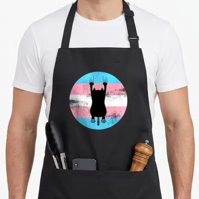Tablier de cuisine noir avec silhouette de chat aux griffes sur fond de drapeau transgenre circulaire