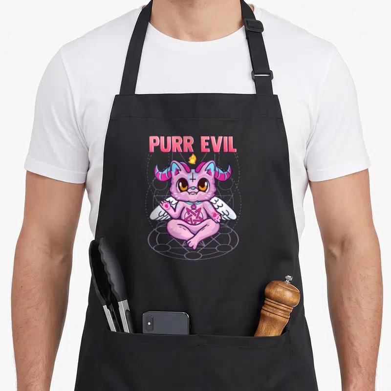 Tablier de cuisine noir avec illustration d'un chat satanique rose assis en tailleur sous le texte Purr Evil