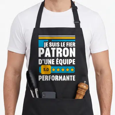 Tablier de cuisine noir avec l'inscription Je suis le fier patron d'une équipe 5.0 performante et cinq étoiles jaunes.