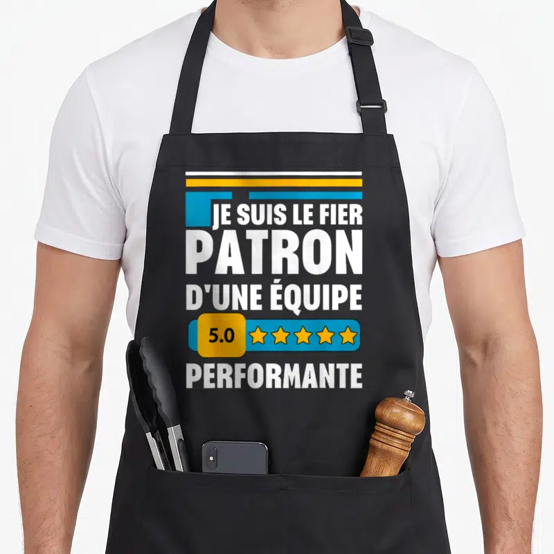 Tablier de cuisine noir avec l'inscription Je suis le fier patron d'une équipe 5.0 performante et cinq étoiles jaunes.