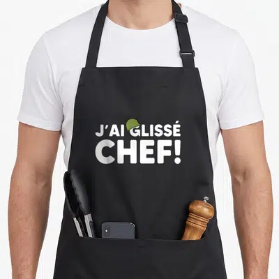 Tablier de cuisine noir avec l'inscription J'ai glissé Chef et un petit casque militaire vert posé sur la lettre G.