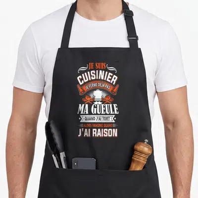 Tablier de cuisine noir avec inscription blanche et orange et illustration de toque de chef.