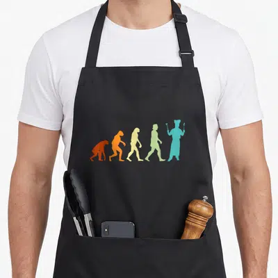 Tablier de cuisine noir avec silhouettes colorées représentant l'évolution vers un chef tenant ustensiles