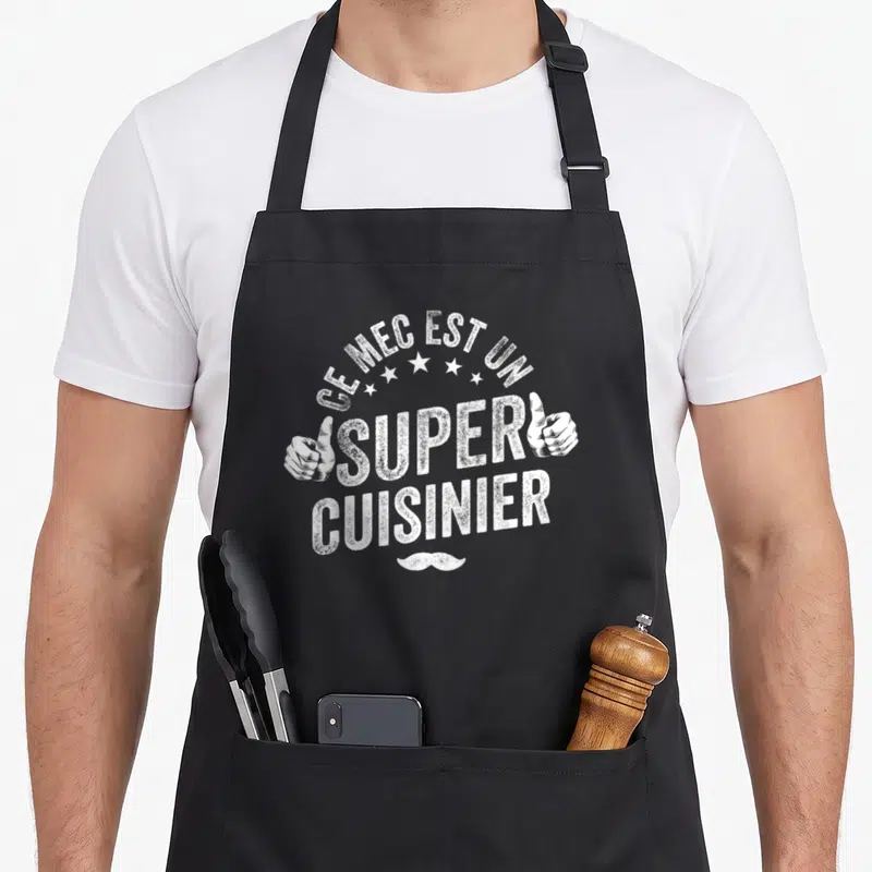 Tablier de cuisine noir avec inscription Ce mec est un super cuisinier, deux mains et une moustache blanche.