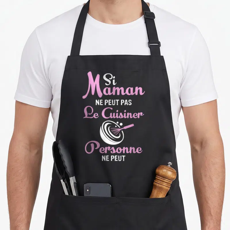 Tablier de cuisine noir avec inscription rose et blanche Si Maman Ne Peut Pas Le Cuisiner Personne Ne Peut et un fouet dans un saladier.