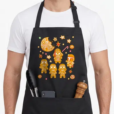 Tablier de cuisine noir avec des biscuits de Noël représentant Darth Vader, les Stormtroopers et la Death Star.