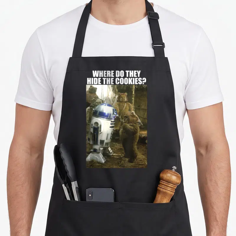 Tablier de cuisine noir avec R2-D2 et des Ewoks posant une question sur le cachet des biscuits