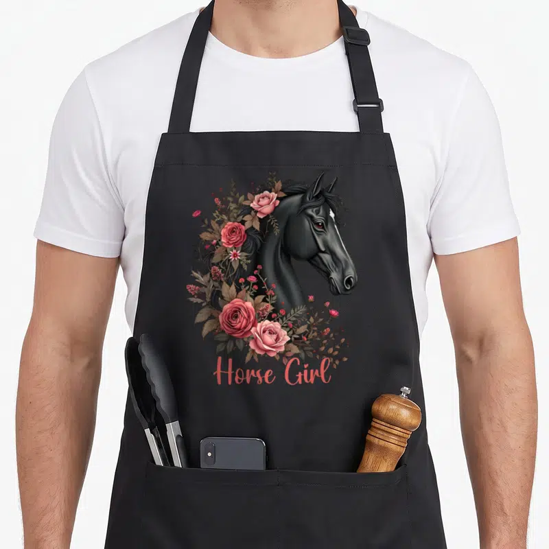 Tablier de cuisine noir avec tête de cheval noir entourée de roses roses et inscription Horse Girl en bas.