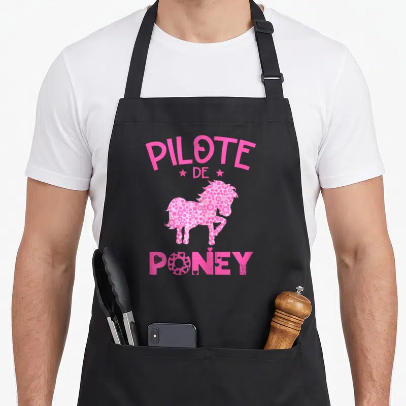 Tablier de cuisine noir avec silhouette de poney rose remplie de motifs floraux et le texte Pilote de Poney en lettres capitales.