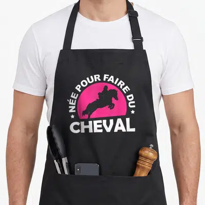 Tablier de cuisine noir avec inscription blanche Née pour faire du Cheval sur fond rose semi-circulaire et silhouette équestre grise.