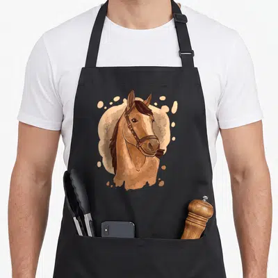 Tablier de cuisine noir avec une illustration colorée représentant la tête d'un cheval marron portant une bride en cuir.
