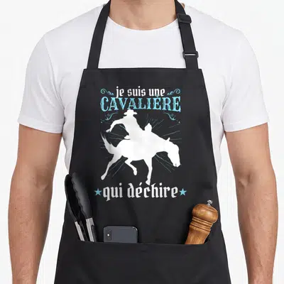 Tablier de cuisine noir avec silhouette blanche de cavalière et texte bleu je suis une cavalière qui déchire.