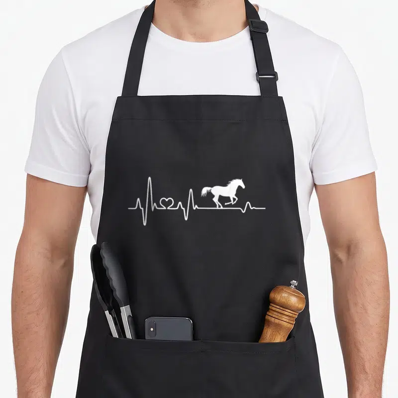 Tablier de cuisine noir avec un motif blanc montrant une ligne de battement de coeur se terminant par la silhouette d'un cheval au galop.