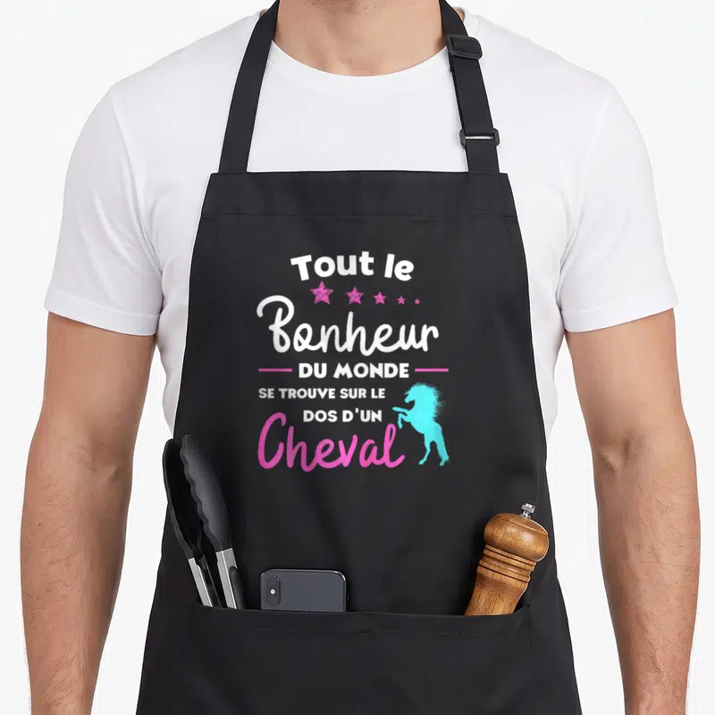 Tablier de cuisine noir avec inscription Tout le Bonheur du Monde et silhouette de cheval sautant en bleu cyan et étoiles roses.