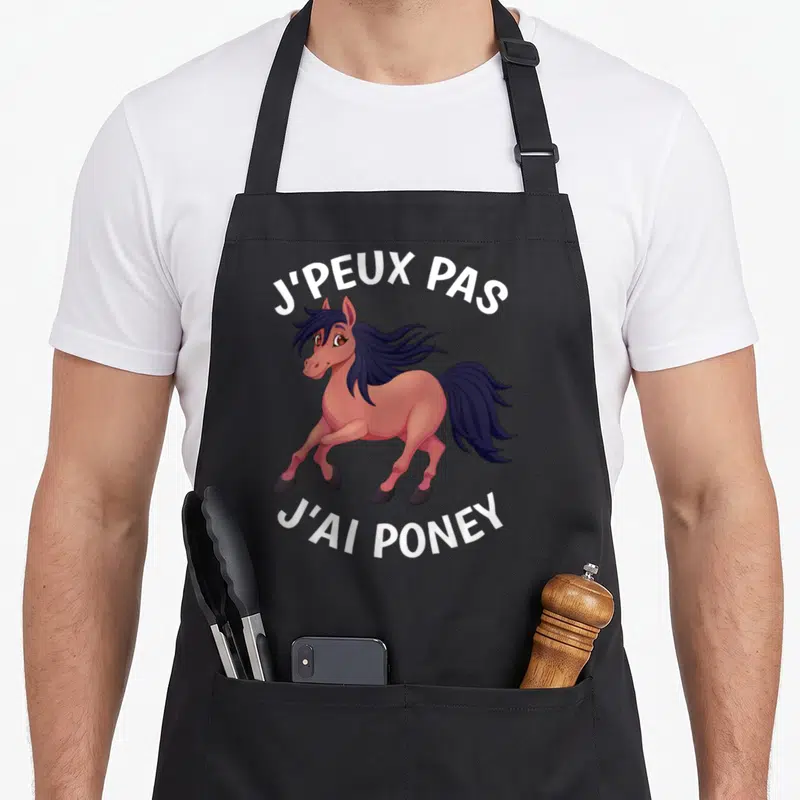 Tablier de cuisine noir avec un poney rose aux cheveux noirs et le texte J'peux pas j'ai poney imprimé en blanc.