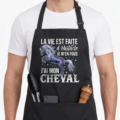 Tablier de cuisine noir avec illustration d'un cheval sautant et texte blanc humoristique sur fond uni.