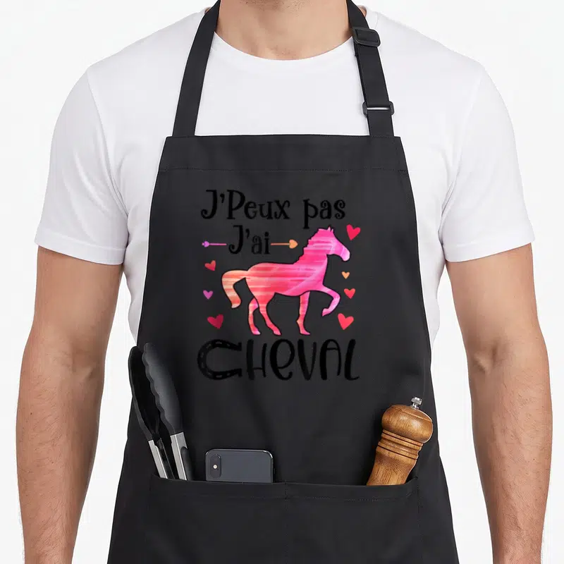 Tablier de cuisine noir avec un étalon rose, des cœurs et le texte J'Peux pas J'ai Cheval en typographie noire stylisée.