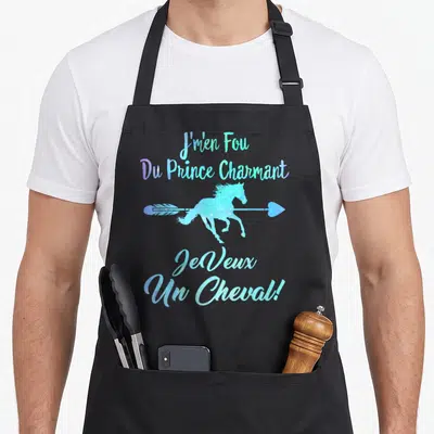 Tablier de cuisine noir avec un cheval bleu traversé par une flèche et le texte J'en fou du prince charmant je veux un cheval.